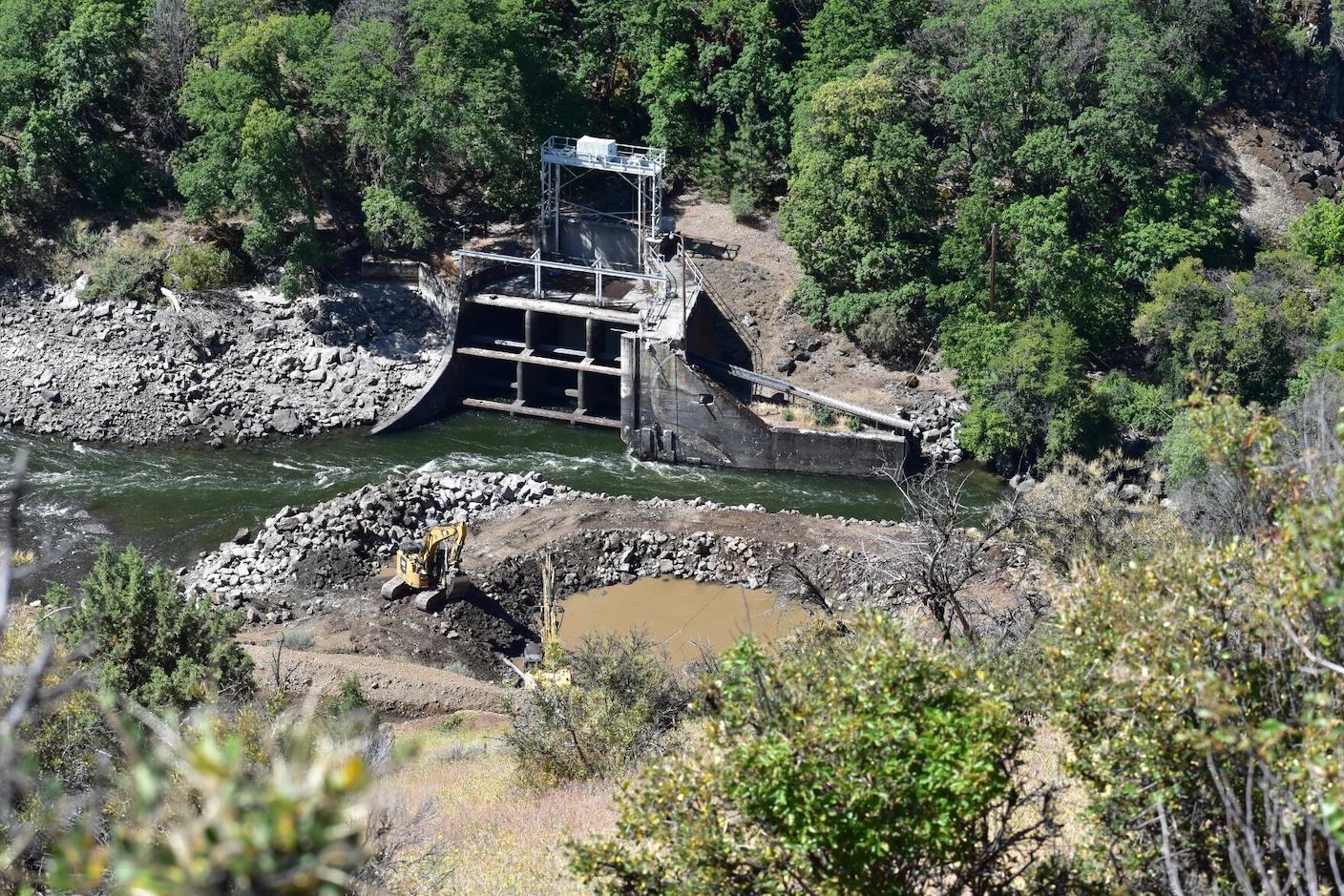 The Klamath River flows by the remaining pieces of the Copco 2 Dam after deconstruction in June 2023. (Credit: Juliet Grable / Jefferson Public Radio)