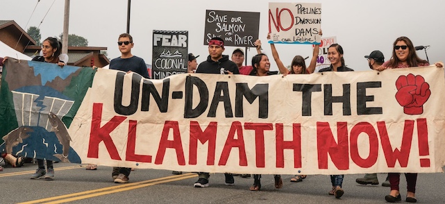 Activist carry sign 'Un-Dam the Klamath Now!' (Photo by Ben Moon)